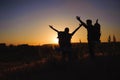 Silhouettes of two hikers with backpacks walking at sunset. Royalty Free Stock Photo