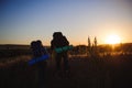 Silhouettes of two hikers with backpacks walking at sunset. Royalty Free Stock Photo