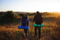 Silhouettes of two hikers with backpacks walking at sunset.