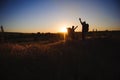 Silhouettes of two hikers with backpacks walking at sunset. Trekking and enjoying the sunset view.