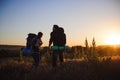 Silhouettes of two hikers with backpacks walking at sunset. Trekking and enjoying the sunset view. Royalty Free Stock Photo