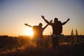 Silhouettes of two hikers with backpacks walking at sunset. Trekking and enjoying the sunset view.