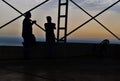 Silhouettes of two men talking and drinking coffee at sunset in exterior place with geometric structures being them in France