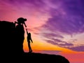 Silhouettes of two people climbing on mountain and helping Royalty Free Stock Photo