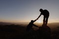 Silhouettes of two people climbing on mountain and helping. Help and assistance concept Royalty Free Stock Photo