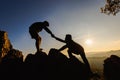 Silhouettes of two people climbing on mountain and helping. Help and assistance concept Royalty Free Stock Photo