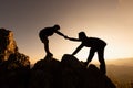 Silhouettes of two people climbing on mountain and helping. Help and assistance concept. Helping hand, Sports training Royalty Free Stock Photo