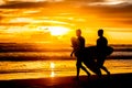 Silhouettes of two surfboarders with boards walking by beach at Royalty Free Stock Photo