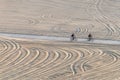 Silhouettes of two unrecognizable bikers riding their bicycles in a beach bike path.