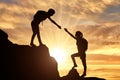 Silhouettes of two women climber climb the mountain helping each other