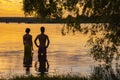 Silhouettes of two young men against the background of water, colored by the sunset Royalty Free Stock Photo