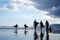 Silhouettes of unrecognizable surfers carrying their surfboard on sunset beach, with a cloud and mirroring in the water Royalty Free Stock Photo