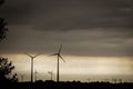 Silhouettes of wind turbines at sunset, cloudy and dusty sky background Royalty Free Stock Photo