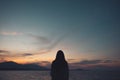 Silhouettes of a woman looking at view on the beach with sea and sunset Royalty Free Stock Photo