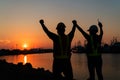 Silhouettes of worker and engineer Raising the hand up and standing on the shipyard. Background is oil storage silo. Teamwork Royalty Free Stock Photo