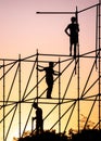 Silhouettes of workers on the scaffolding against the backdrop of the colorful sunset sky.