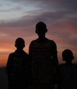 Silhouettes of Young African Girl With Her Younger Brothers Posing At A Pale Red Blue Sunset