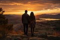 Silhouettes of a young couple admiring beautiful view on sunset. Man and woman looking at scenic evening landscape