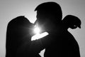 Silhouettes of young couple kissing on sunny summer day