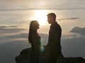 Silhouettes of young couple standing on a mountain and looking to each other on beautiful sunset background. Love of guy Royalty Free Stock Photo