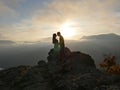 Silhouettes of young couple standing on a mountain and looking to each other on beautiful sunset background. Love of guy Royalty Free Stock Photo