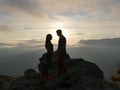 Silhouettes of young couple standing on a mountain and looking to each other on beautiful sunset background. Love of guy Royalty Free Stock Photo