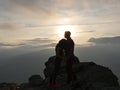 Silhouettes of young couple standing on a mountain and looking to each other on beautiful sunset background. Love of guy Royalty Free Stock Photo