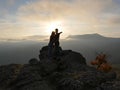 Silhouettes of young couple standing on a mountain and looking to each other on beautiful sunset background. Love of guy Royalty Free Stock Photo