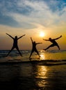 Silhouettes of young group of people jumping on the beach at sun Royalty Free Stock Photo