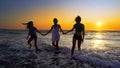 Silhouettes of young group of people jumping in ocean at sunset Royalty Free Stock Photo