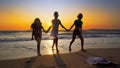 Silhouettes of young group of people jumping in ocean at sunset Royalty Free Stock Photo