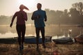 Silhouettes of young man and woman running by the lake or river in the early autumn morning