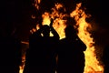 Silhouettes young people around roaring flames fire bonfire