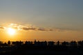 Silhouettes of young people sitting on the St. Petersburg roof against the background of the orange sunset