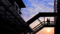 Silhouettwe couple walking on footbridge against sunset sky background in evening time Royalty Free Stock Photo