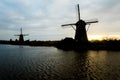 Silhoutte of dutch traditional old wind mills along the river in the romantic sunset Royalty Free Stock Photo