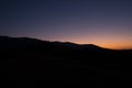 Silhoutte of evening mountains with trees on it and moon on the sky