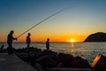 Silhoutte of three men fishing at sunset Royalty Free Stock Photo