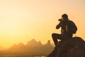 Silhuette of photographer traveler taking photo of beautiful sunset from top of the mountain