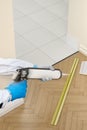 Silicone sealant gun glue strip between wooden floor and tiles