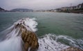 Silk effect of the waves breaking against the rocks with La Concha beach in San Sebastian (Spain) in the background Royalty Free Stock Photo