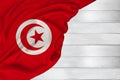 Silk national flag of modern country Tunisia lies with soft folds on a white wood background for text, concept of tourism, economy