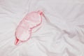 Silk pink eye mask lying on the white bedding in the morning, Royalty Free Stock Photo