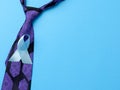 Silk purple mens tie and blue ribbon folded in a loop on blue background