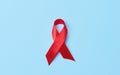 A silk red ribbon in the form of a bow on a blue background, a symbol of the fight against AIDS and a sign of solidarity and