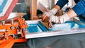 silk screen printmaking. male hands with a squeegee. serigraphy production selective focus photo. printing images on clothes by