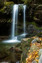 Silky Rainbow Falls waterfall with rocks and fall colored leaves in the foreground in the Great Smoky National Park, Tennessee, US