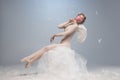 Silly mood. Beautiful young girl, graceful ballerina in image of angel with wings sitting on cloud isolated on white Royalty Free Stock Photo