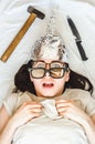 Silly paranoid woman wears tinfoil hat and sleeps with weapon and different glasses because of paranoia