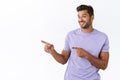 Silly smiling gay man invite check out and see nice offer, pointing left and gazing camera with satisfied outgoing Royalty Free Stock Photo